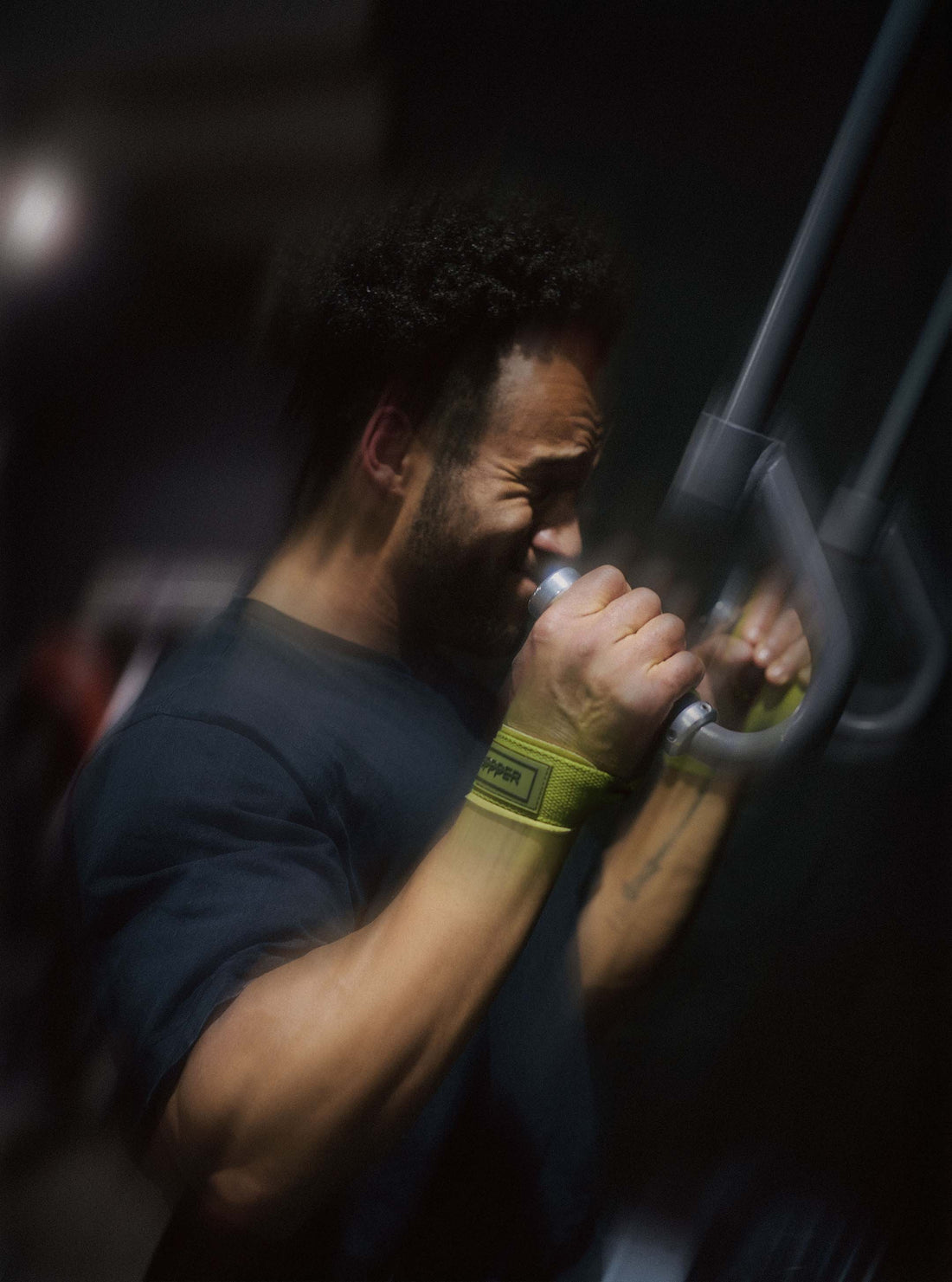 man using upper body gym machine while wearing uppper lifting straps