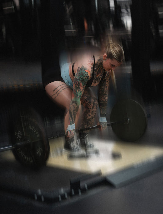 woman doing romanian deadlifts wearing uppper lifting straps and lever belt