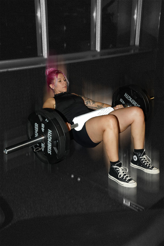 woman doing barbell hip thrust with uppper barbell pad