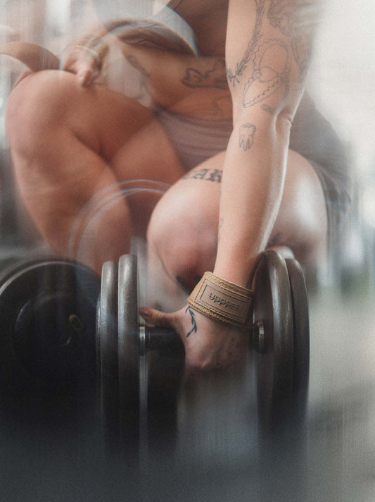 woman gripping dumbbell with uppper lifting straps