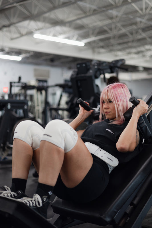 woman doing leg workout with uppper lifitng belt and knee sleeves